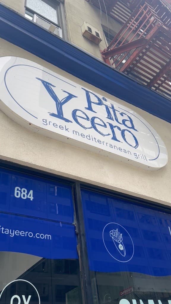 Pita Yeero storefront signage on a New York street, with a clear oval logo and window branding.