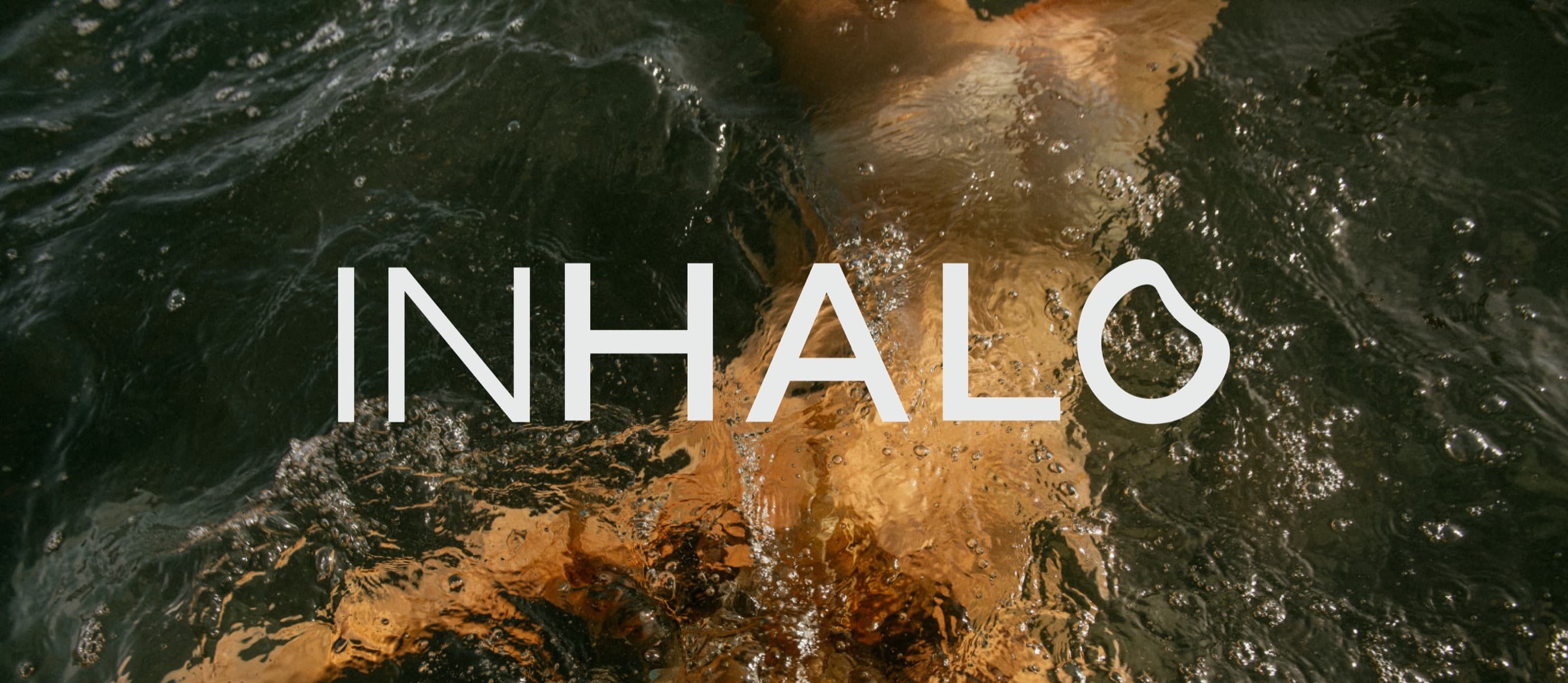 Inhalo wordmark over a swimmer seen through dark rippling water