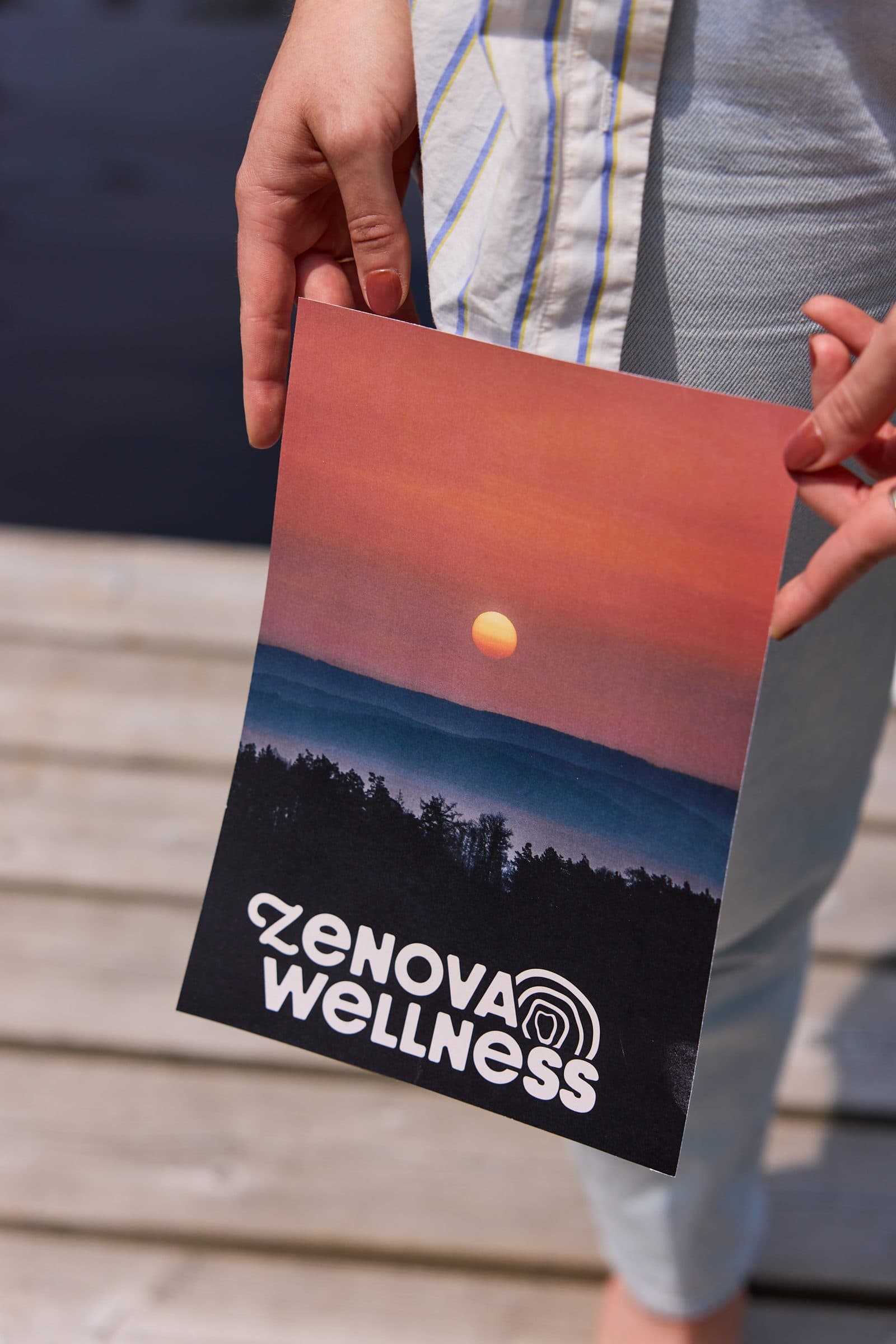 Printed Zenova Wellness brand presentation held outdoors against a sunset landscape
