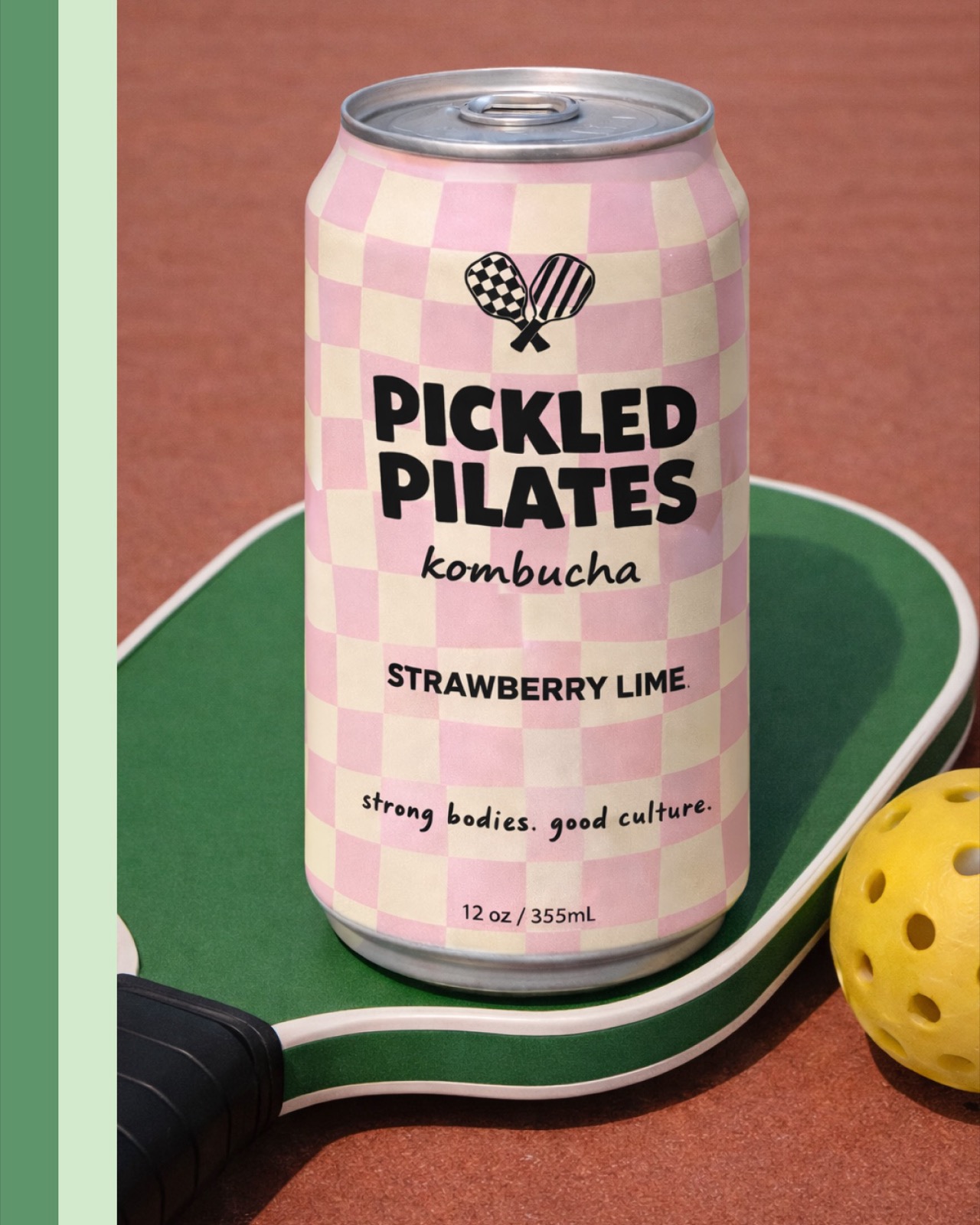 Pickled Pilates Strawberry Lime kombucha can on a paddle with pickleball